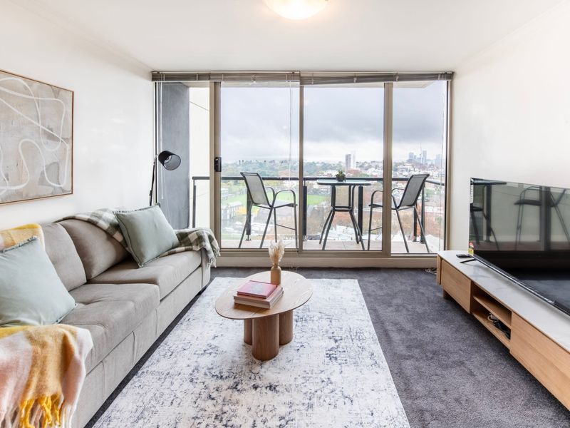 Bright living room with floor to ceiling windows and sweeping city view