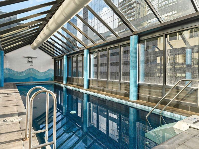 Indoor shared, heated pool with glass roof and city outlook