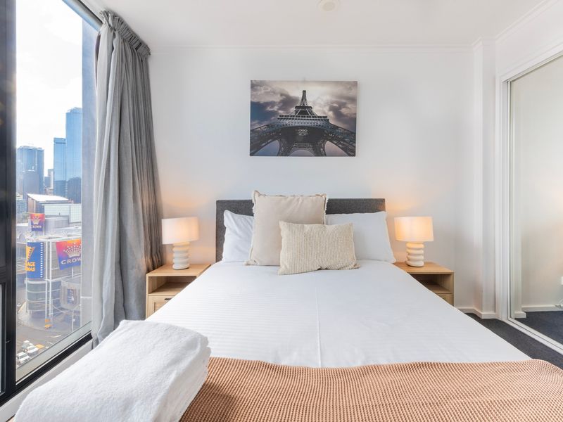 Cozy, bright bedroom with a soft bedside lamp and outside view