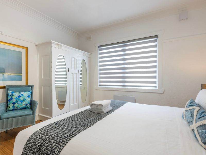 Spacious king bedroom with classic detailing, timber floors and built in wardrobe