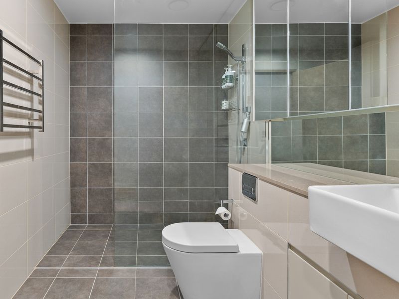 Modern bathroom vibes: Shower, toilet, and all the essentials—body wash, shampoo, and a huge mirror.