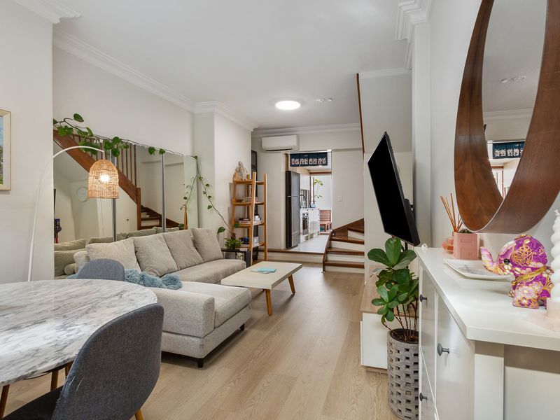 Spacious and inviting living room with a TV, dining table, and chic mirrors.