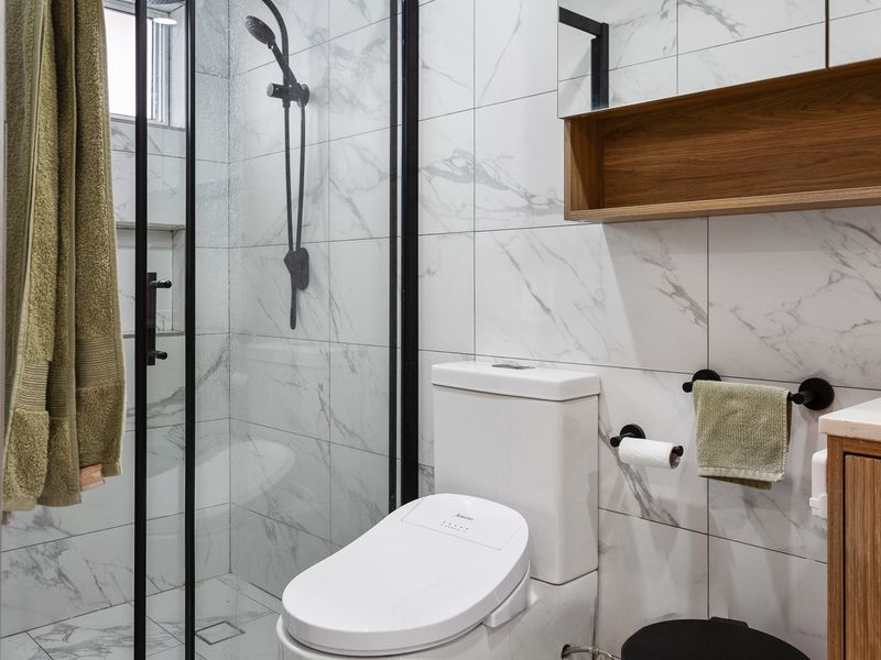 Practical and sleek bathroom with a shower, sink, toilet, and perfect mirror