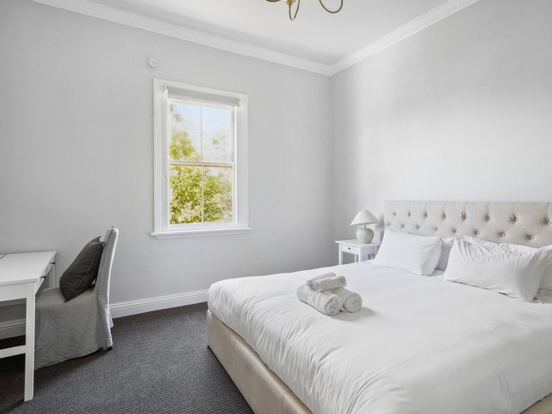 Bright and serene bedroom with a cosy workspace for added convenience.