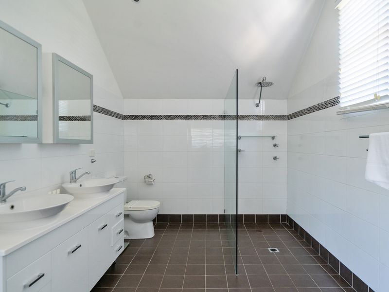 Spacious modern bathroom featuring dual sinks and a sleek walk-in shower.