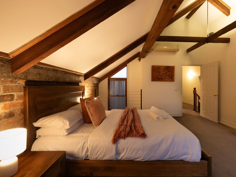 Rustic Sanctuary: Warmly lit loft bedroom beautifully showcasing architectural lines and exposed brick details.