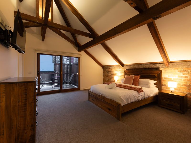 Character Loft Bedroom: Stunning master retreat boasting dramatic cathedral ceilings and exposed structural timber beams.