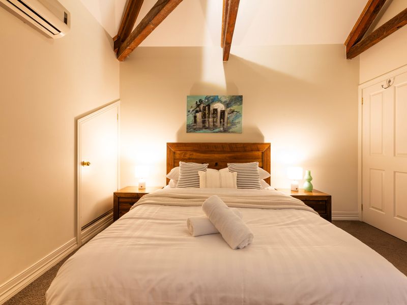 Rustic Sanctuary: A beautifully framed loft space mixing architectural timber elements with crisp white bedding.