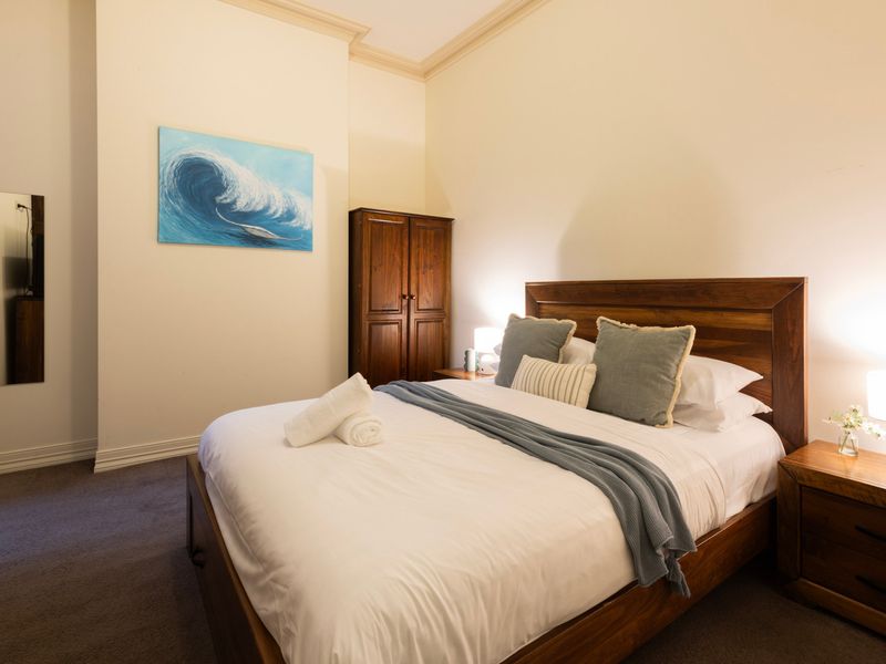 Serene Sleep: A restful bedroom space featuring rich timber furniture and cool, ocean-themed artwork.