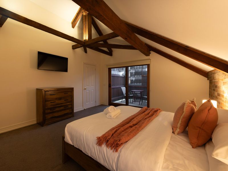 Loft Comfort: Beautifully styled bedroom highlighting the spacious vaulted ceilings and premium timber furnishings.
