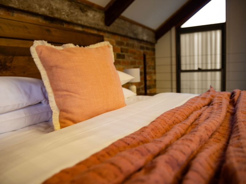Cozy Textures: Close-up of premium linens paired with warm terracotta cushions and rustic timber accents.
