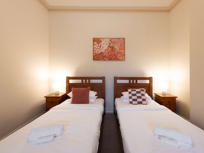 Symmetrical Style: Clean lines and warm red accents define this comfortable, twin-share sleeping arrangement.