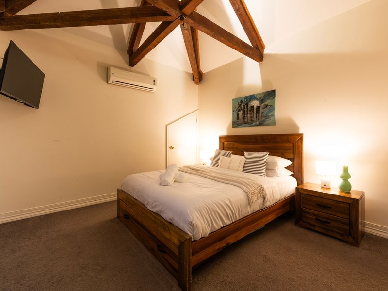 Vaulted Loft Suite: Dramatic character bedroom showcasing striking exposed ceiling beams and ambient lighting.