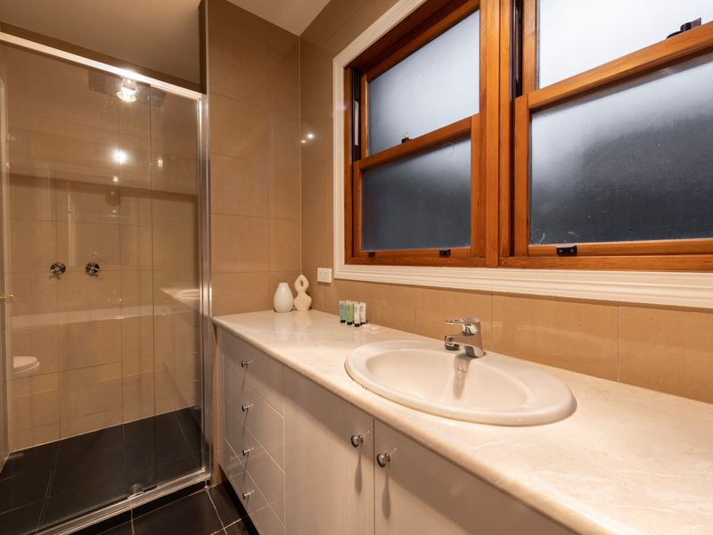 Sunlit Vanity: Sleek, expansive bathroom counter featuring classic timber-framed windows and a glass shower.