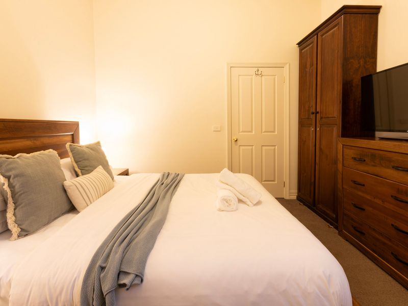 Fully Equipped Comfort: A well-appointed bedroom complete with a TV setup, ample wardrobe storage, and soft textures.