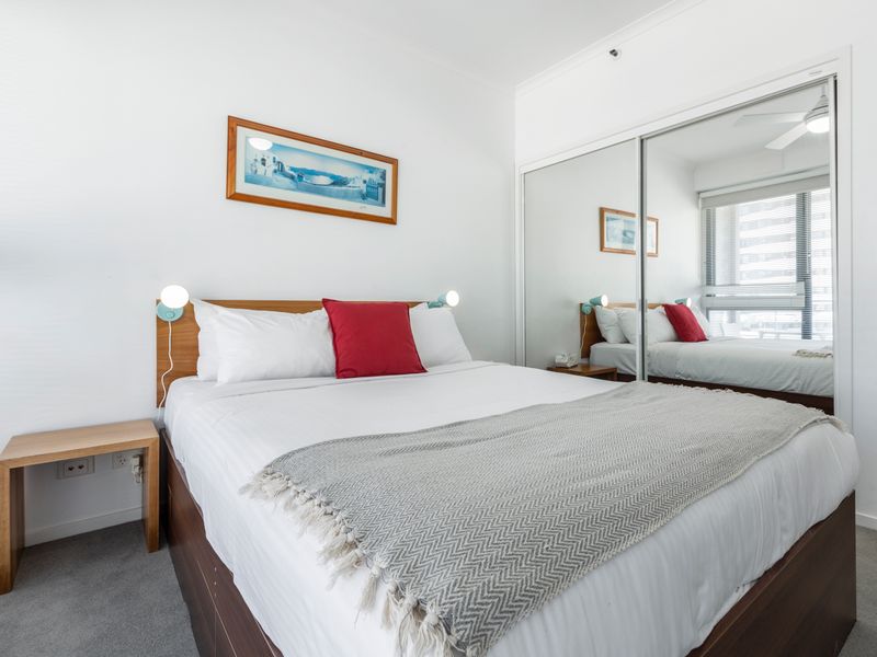 First bedroom featuring a double bed, ceiling fan and soft natural light from the window.