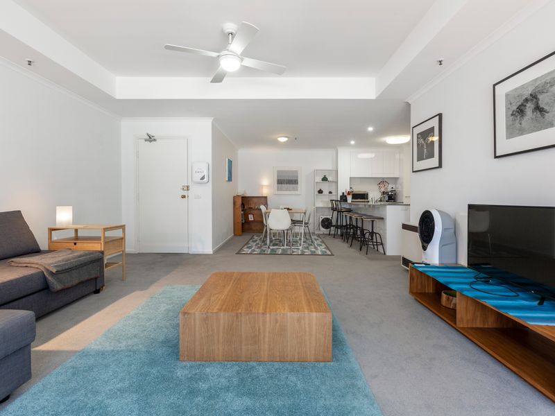 Bright open plan living area featuring comfortable seating, a TV and large windows that fill the space with natural light.