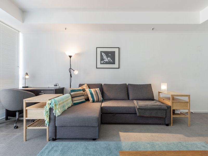Comfortable lounge space with large sofa, TV and warm lighting, ideal for relaxing after a day in the city.