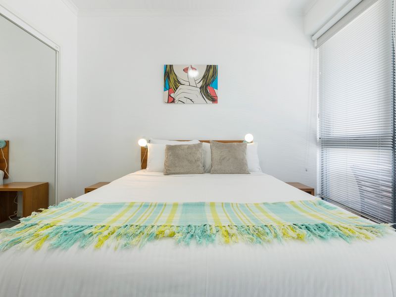 Second bedroom styled with double bed, bedside tables and soft natural light from the large window.