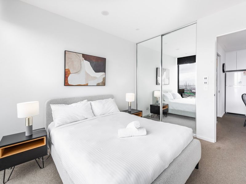 Bright and inviting bedroom with plush bedding and mirrored wardrobes.