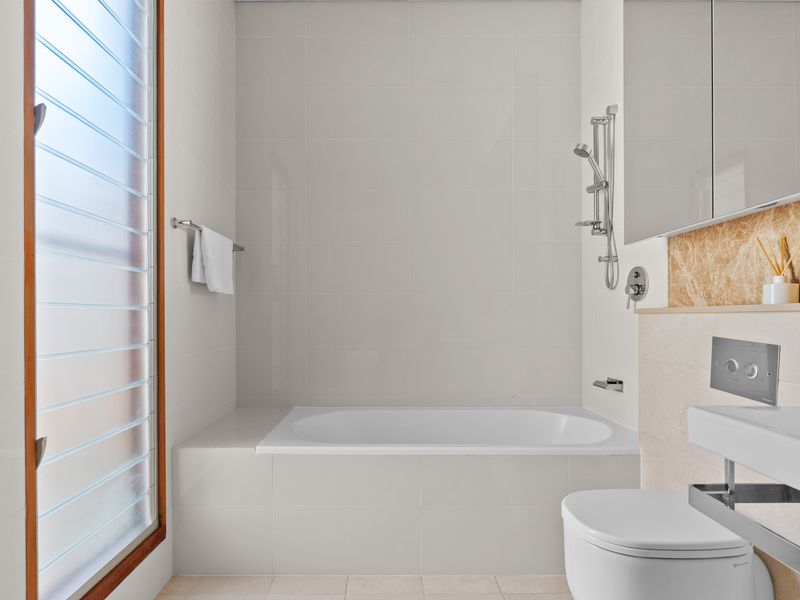 Clean and modern bathroom with a bath and shower combo.