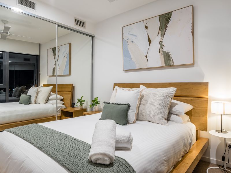 Bedroom 2: Sleep in Scandinavian Style. This designer bed features a beautifully curved natural timber headboard and frame. The crisp, clean white linen is dressed with five plump pillows.