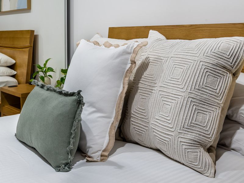 Bedroom 2: Sleep in Scandinavian Style. This designer bed features a beautifully curved natural timber headboard and frame. The crisp, clean white linen is dressed with five plump pillows.