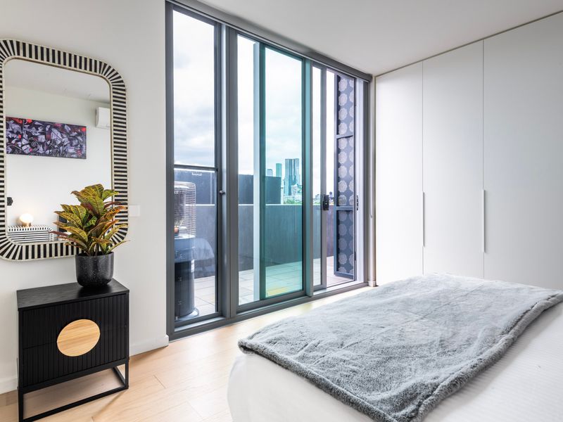 Master bedroom with balcony access and serene cityscape views.