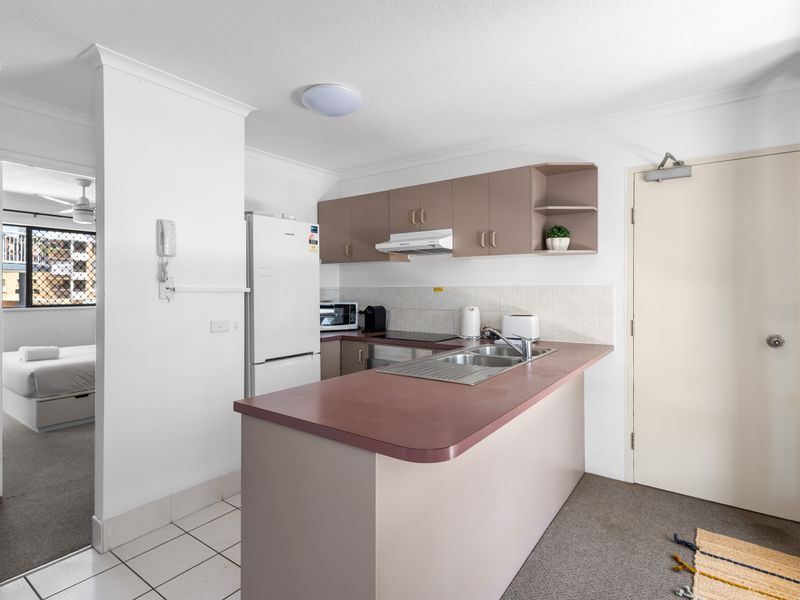 Open and accessible kitchen space. The kitchen features a compact, functional layout with ample counter space. It includes a full-sized fridge, oven, stovetop, and dishwasher. Its open position ensures the cook remains connected to the adjacent living and