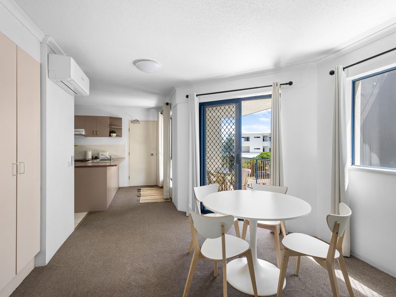 The dining area features a bright, circular white table with four chairs. It is strategically placed to flow seamlessly between the lounge and the kitchen, making it an ideal gathering spot for meals, planning, or games. This area is easily accessible fro