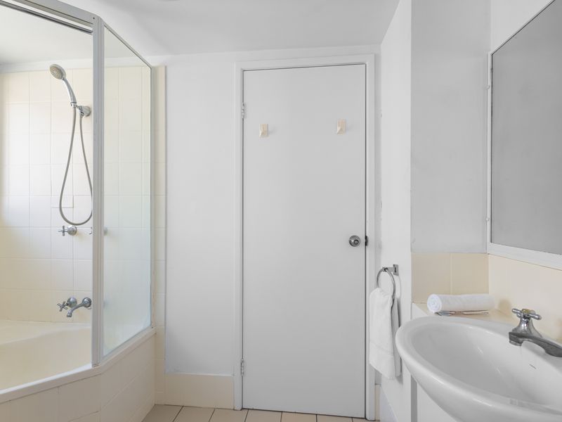 The clean, modern bathroom features a vanity sink and a shower area. It is well-lit and includes essential amenities.