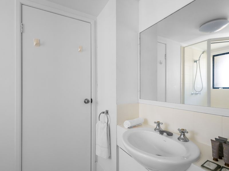 The clean, modern bathroom features a vanity sink and a shower area. It is well-lit and includes essential amenities.