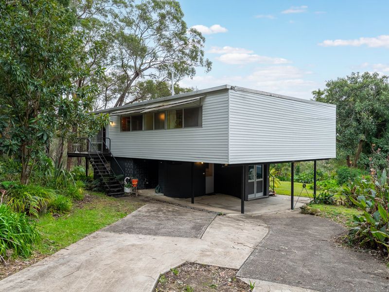 A unique, elevated home nestled among lush greenery, showcasing a blend of modern design and natural surroundings.