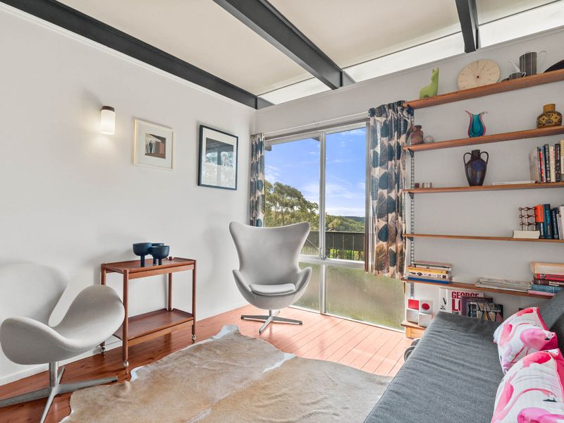 A cozy living space with mid-century modern furniture, featuring the iconic Egg chair and a view of the outdoors.