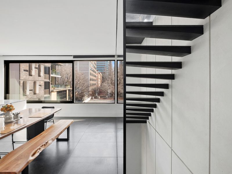 A modern interior space featuring a dining area and a striking staircase.
