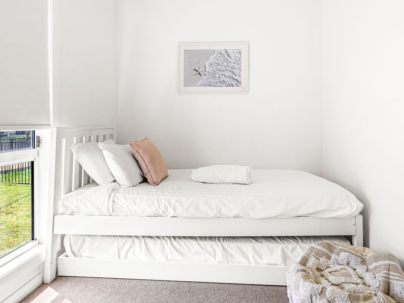 Sunny single room with trundle bed and pastel cushions