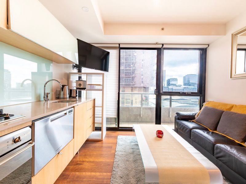 Bright open-plan living area with kitchenette and balcony views of the city skyline