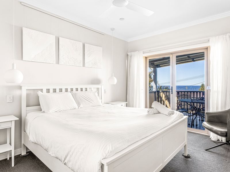 Bright bedroom with balcony access and ocean view.