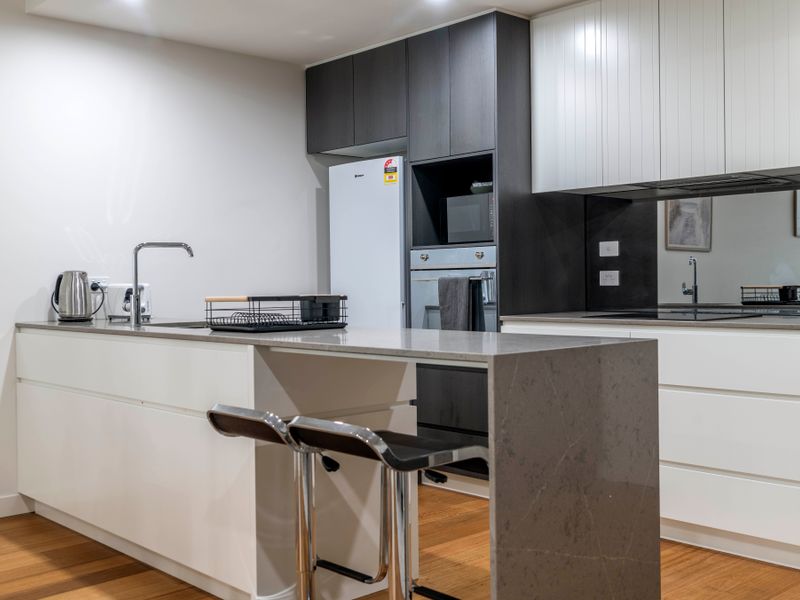 Sleek kitchen with stone benchtops and stainless steel appliances