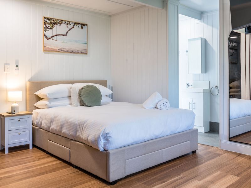 Modern bedroom with queen bed, bedside lighting, and wooden flooring