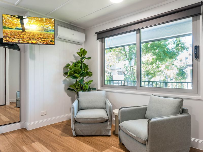 Comfortable sitting area with armchairs, flat-screen TV, and natural light