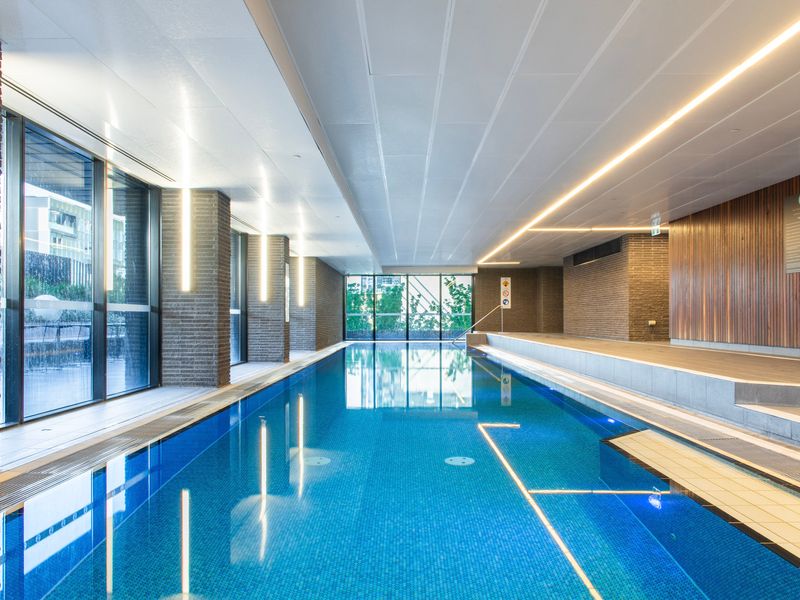 Indoor swimming pool with seating area and natural light