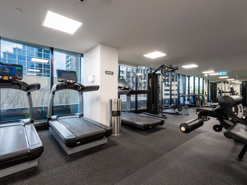Fully equipped gym with treadmills, weights, and large windows