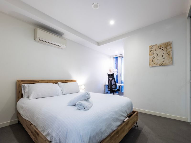 Minimalist bedroom with wooden frame bed and air conditioning