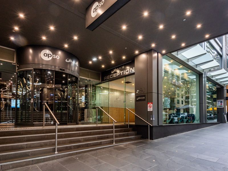 Building entrance with glass façade, stair access, and city street view