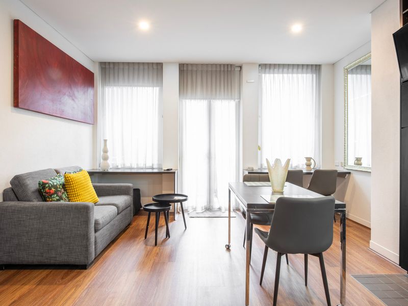 Bright living room with sofa, dining table, and large windows