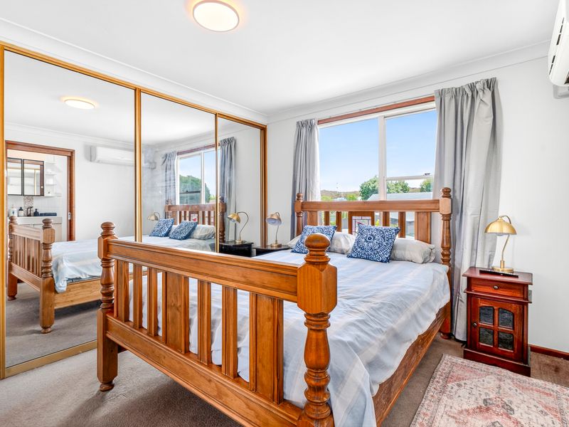 Bright master bedroom with large windows and warm timber tones
