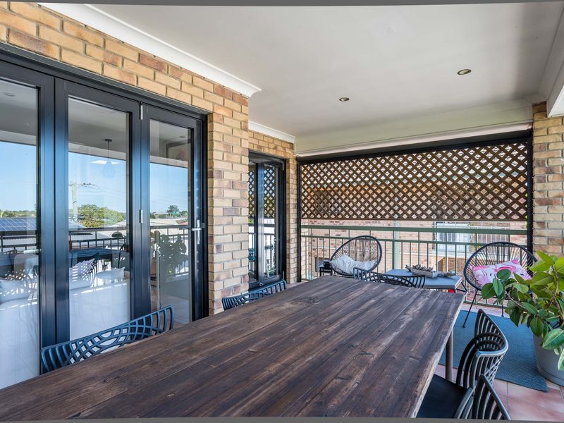 Large covered balcony with dining table and indoor-outdoor flow