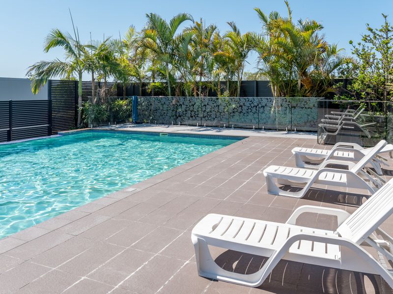 Outdoor swimming pool with sun loungers and tropical surrounds.