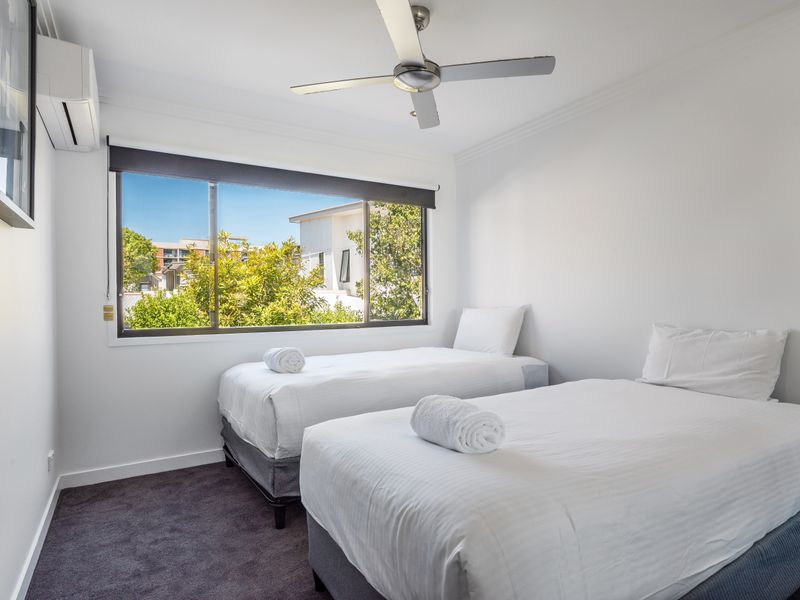 Twin bedroom with single beds and ceiling fan.